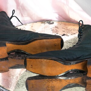 May include: A pair of black lace-up boots with leather soles. The boots have a rounded toe and a low heel. The soles are marked with the size "11" and "16".