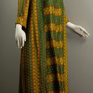 May include: A long green and yellow patterned dress with a floral design. The dress has a round neckline and three-quarter sleeves.