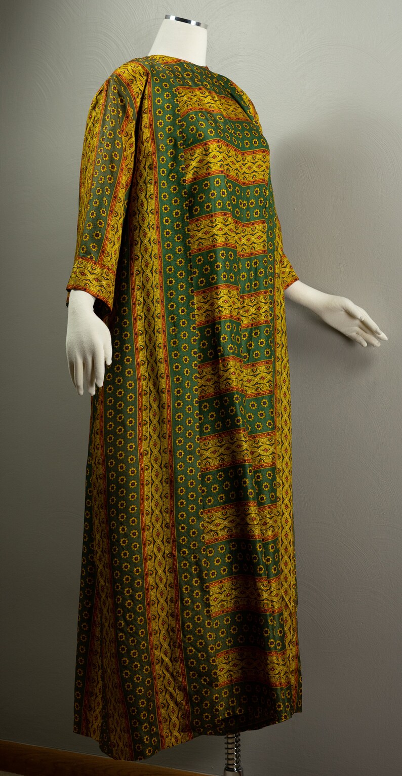 May include: A long green and yellow patterned dress with a floral design. The dress has a round neckline and three-quarter sleeves.