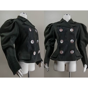 May include: A dark green double-breasted jacket with puffed sleeves and decorative embroidery. The jacket has large, round buttons with a pearl-like finish.
