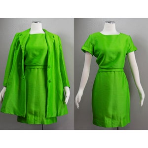 Puede incluir: Un conjunto de vestido y chaqueta de color verde brillante. El vestido tiene una silueta simple y ajustada y mangas cortas. La chaqueta tiene un cuello clásico y mangas largas.