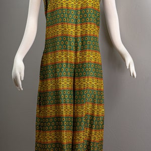 May include: A sleeveless maxi dress with a green and yellow geometric pattern. The pattern features a repeating design of small flowers and stripes.