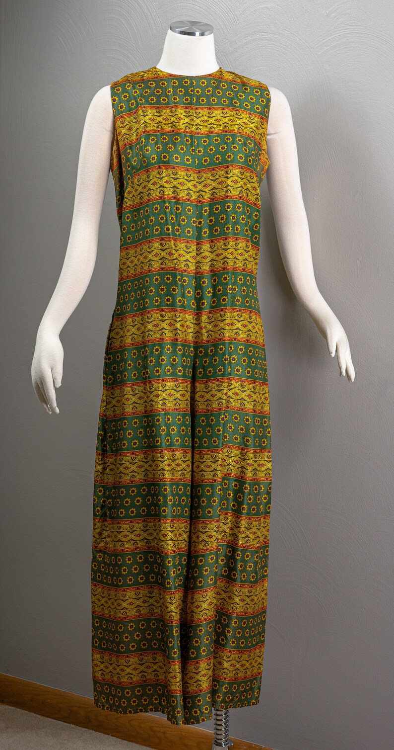 May include: A sleeveless maxi dress with a green and yellow geometric pattern. The pattern features a repeating design of small flowers and stripes.