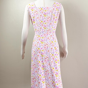 Puede incluir: Vestido sin mangas con estampado floral en blanco, rosa, amarillo y lavanda. El vestido tiene un escote cuadrado y una silueta entallada. La tela est&aacute; cubierta con un delicado estampado floral. El vestido se muestra en un maniqu&iacute;.