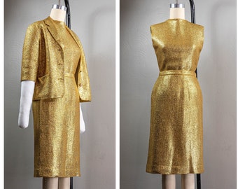 May include: A gold metallic dress and matching jacket set. The dress and jacket have a subtle ribbed texture. The dress is sleeveless and has a fitted silhouette. The jacket has a short sleeve and a single button closure.