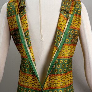 May include: A green and yellow patterned sleeveless dress with a zipper down the back.