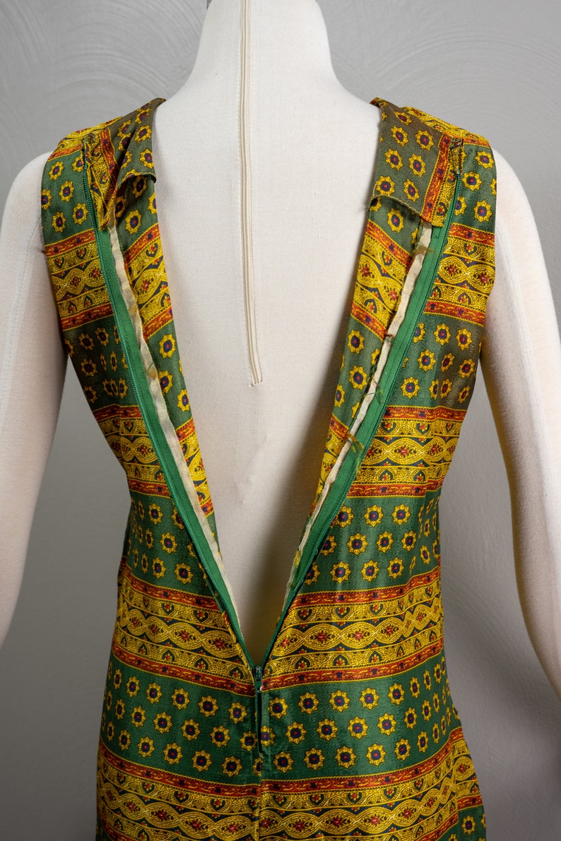 May include: A green and yellow patterned sleeveless dress with a zipper down the back.