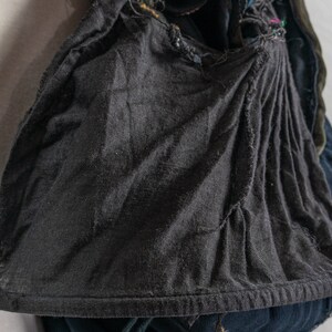 May include: A black hooded garment with a drawstring closure. The hood is made of a soft, textured fabric and has a gathered look. The garment is worn over a blue denim jacket.