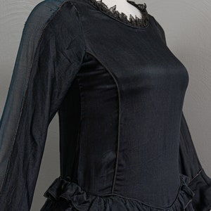 May include: A black dress with a lace neckline and a tiered ruffle skirt. The dress has long sleeves and a fitted bodice.