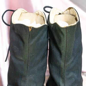 May include: A pair of black canvas boots with laces. The boots have a white lining and are worn.