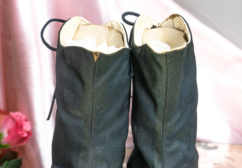 May include: A pair of black canvas boots with laces. The boots have a white lining and are worn.
