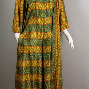 May include: A long green and yellow patterned dress with a floral design. The dress has a long sleeve and a loose fit.