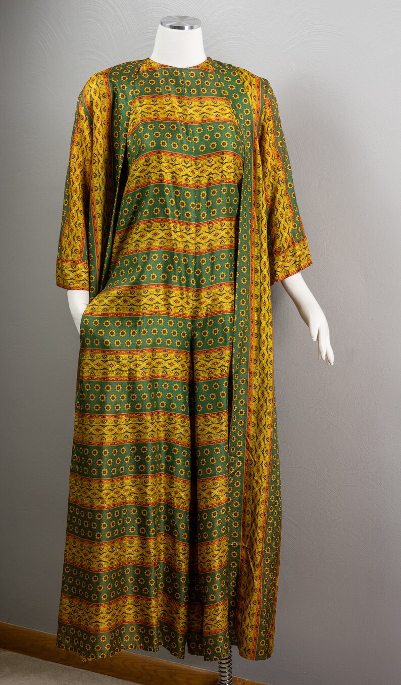 May include: A long green and yellow patterned dress with a floral design. The dress has a long sleeve and a loose fit.