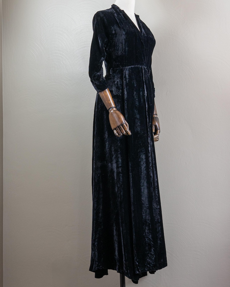 K&ouml;nnte beinhalten: Ein langes schwarzes Samtkleid mit V-Ausschnitt und Dreiviertel&auml;rmeln.