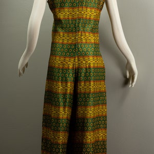 May include: A sleeveless jumpsuit with a green and yellow geometric pattern. The jumpsuit has a wide leg and a fitted bodice.
