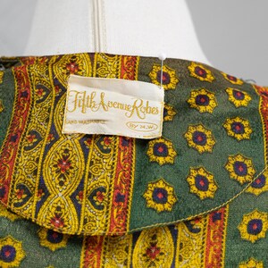 May include: A green and yellow patterned fabric with a white label that reads "Fifth Avenue Robes, Hand Washable, By M.W."