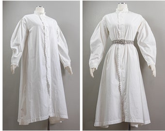 May include: A white cotton dress with a lace trim and a button-up front. The dress has long sleeves and a gathered skirt. The dress is shown on a mannequin.