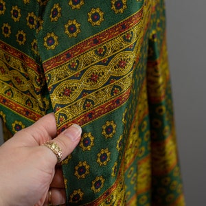May include: Green fabric with a repeating pattern of yellow and blue flowers and a red, yellow, and blue paisley border.