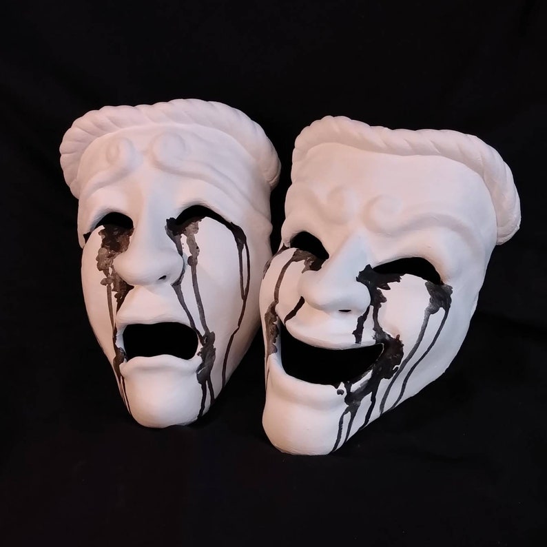 Puede incluir: Dos m&aacute;scaras teatrales blancas con pintura negra goteando por sus caras. Una m&aacute;scara est&aacute; llorando y la otra est&aacute; riendo.