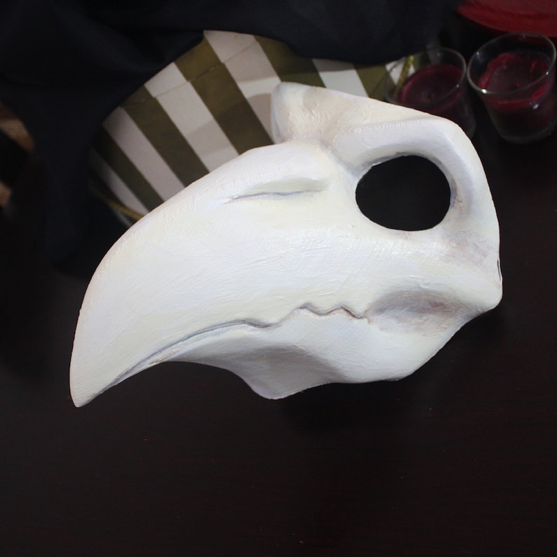 May include: A white bird mask with a long beak and a large eye hole. The mask is made of a lightweight material and is perfect for a costume or theatrical performance.