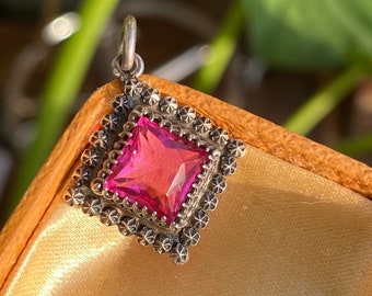 May include: A pink gemstone pendant with a silver setting. The pendant is in a small box with a satin lining.
