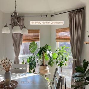 May include: A dining room with neutral-toned curtains, bamboo shades, and lush green plants. A chandelier hangs above a white oval table. The text "For every room in your home" is visible.