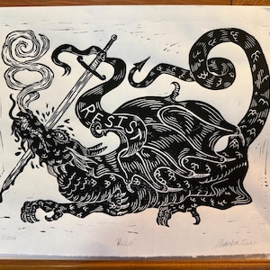 May include: Black and white linocut print featuring a dragon-like creature pierced by swords, with the word "RESIST" incorporated into its form. The dragon exhales smoke. The print is signed and dated.