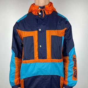 Puede incluir: Una chaqueta de color bloque azul, naranja y turquesa con cierre de presión y capucha. La chaqueta tiene el texto "Neo Tech 88" en la manga derecha.