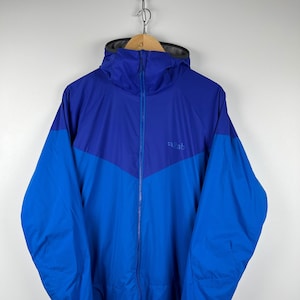 May include: A blue and purple hooded jacket with a zipper closure and the word "rab" on the front.