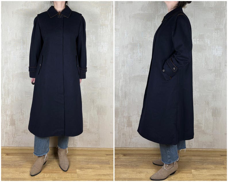 May include: A long, navy blue coat with a collar and pockets. The coat is made of a thick, warm fabric and has a classic, timeless style.