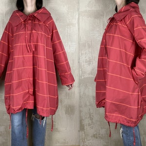 May include: A red and orange striped jacket with a large collar and a drawstring at the waist.