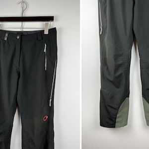 May include: Black hiking pants with zippered pockets and a red logo on the right leg.