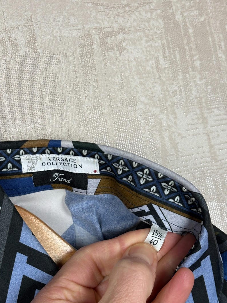 May include: Versace Collection shirt with a geometric pattern in blue, black, and brown. The collar features a floral design. The label reads "Versace Collection Trend" and size 15 1/2, 40.