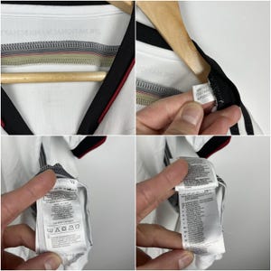 May include: White soccer jersey with black and red trim. The jersey has the text "DIE NATIONALMANNSCHAFT" on the back. The tag on the jersey reads "GR.13  G87444  APU002".