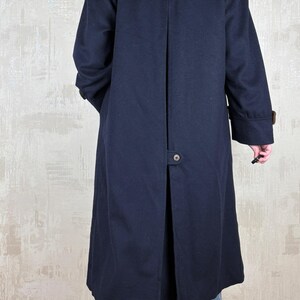 May include: A long navy blue coat with a brown trim around the collar and cuffs. The coat has a single button closure at the back.