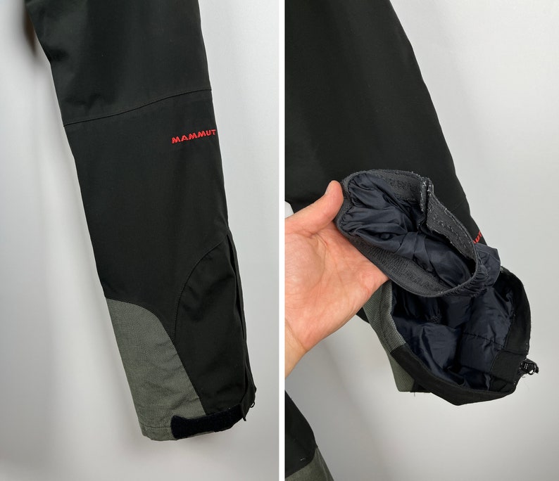 May include: Black ski pants with a gray panel on the lower leg. The pants have a zipper on the lower leg and the word "MAMMUT" is embroidered on the right leg.
