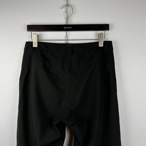 May include: Black pants with a waistband and a zipper fly.