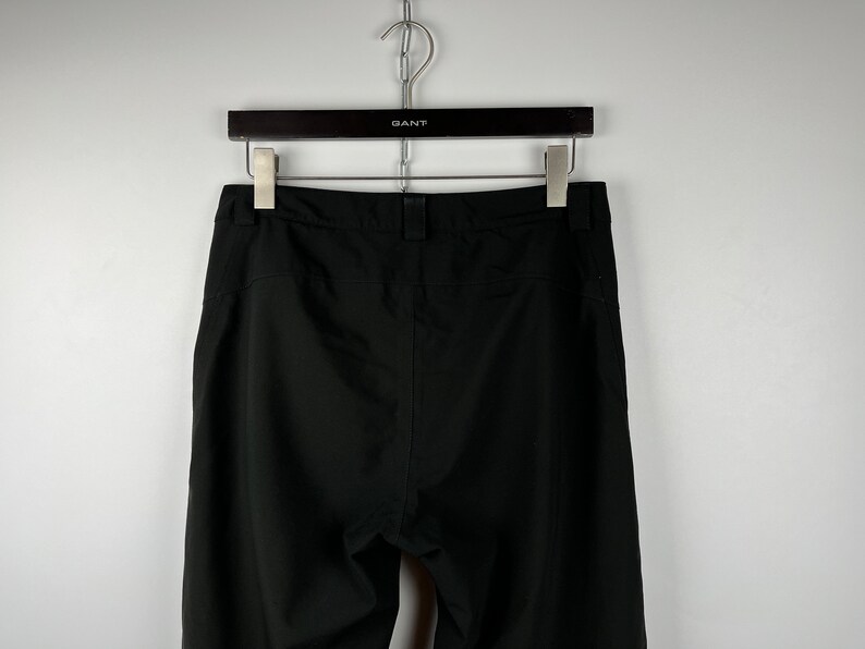 May include: Black pants with a waistband and a zipper fly.