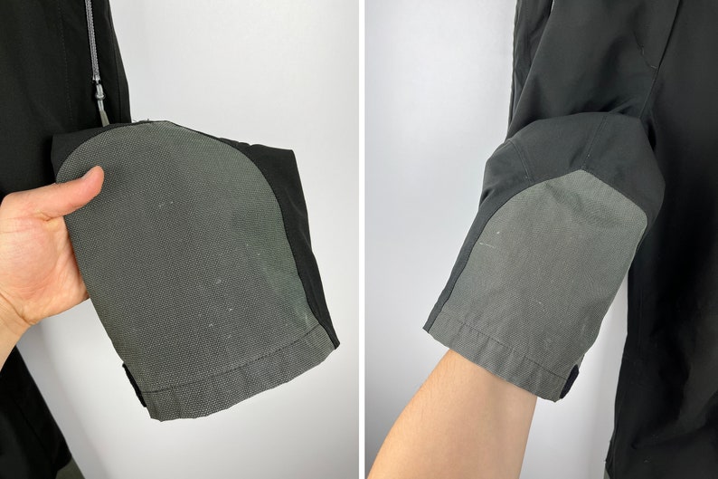 May include: Close-up of black pants with gray reinforced knee patches. The pants are made of a lightweight, water-resistant fabric.