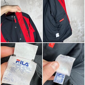May include: Black and red Fila jacket. The jacket has a black body with red accents on the shoulders, sleeves, and collar. The jacket has a zipper closure and multiple pockets. The Fila logo is visible on a tag.