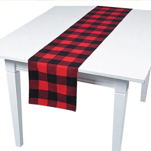 May include: Red and black checkered table runner. The runner is made of a soft, woven fabric and is perfect for adding a touch of rustic charm to any table setting.