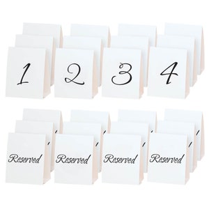 May include: Set of 20 white table cards with black calligraphy. The cards are numbered 1 through 4 and also have the word "Reserved" written on them.
