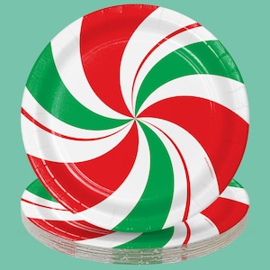 May include: A stack of red and green paper plates with a peppermint swirl design. The plates are made of paper and are disposable. The plates are perfect for a holiday party or gathering.