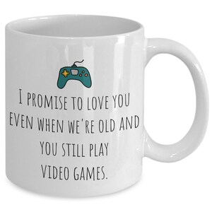 May include: White ceramic coffee mug with a black and green video game controller graphic and the text "I promise to love you even when we're old and you still play video games."