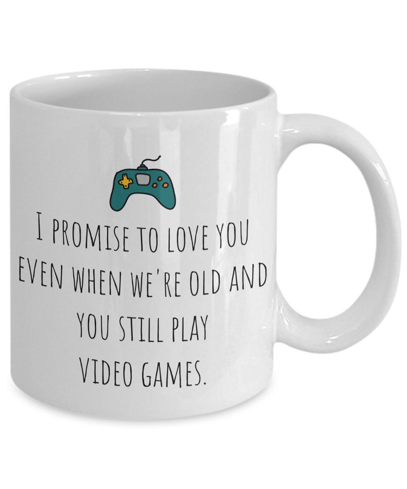 May include: White ceramic coffee mug with a black and green video game controller graphic and the text "I promise to love you even when we're old and you still play video games."