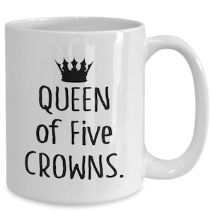 May include: White ceramic mug with a black crown and the text "QUEEN of Five CROWNS."