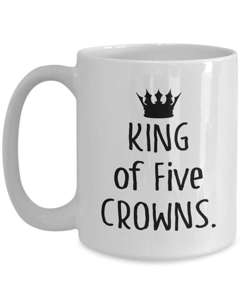 May include: White ceramic coffee mug with a black crown and the text "King of Five Crowns."