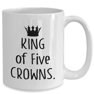 May include: White ceramic mug with a black crown and the text "KING of Five CROWNS."