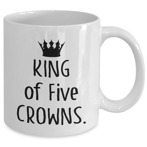 May include: White ceramic coffee mug with a black crown and the text "KING of Five CROWNS."