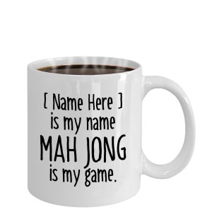 May include: White ceramic coffee mug with black text that reads "[ Name Here ] is my name MAH JONG is my game."